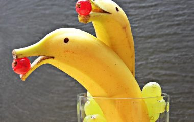 金黄成熟的大香蕉整串悬挂在通风木架上，背景为北欧风格白色厨房，自然光线从侧窗射入，果皮纹理清晰可见